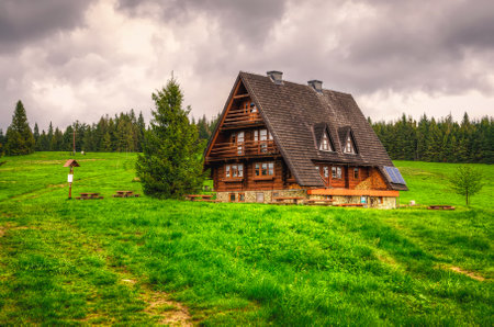 Zywiec Beskids, Poland - May 27, 2015: Mountain hostel called Krawcow Wierch. View of wooden hut on the glade at the green wooded hill, Beskids mountains in spring season.のeditorial素材