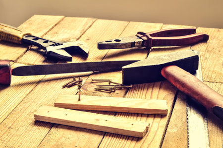 Renovation tools on the table. Hammer, flat file, pliers, screwdriver, monkey wrench, screws, boards and blade on natural wooden background.の写真素材