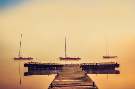 Foggy morning on the lake. Boats and wooden pier at Lake Parpocany in Tychy, Poland.の写真素材