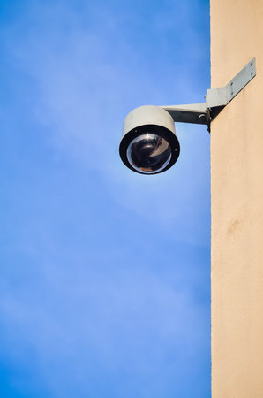 Municipal monitoring on the wall of the tenement house. Security camera on building against a blue...