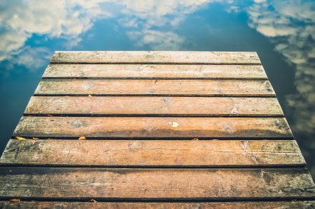 Background with wooden planks and the reflection of clouds in the water. Wooden pier and clouds reflecting in the lake.の写真素材
