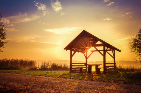 Autumn morning landscape. Wooden shelter on the lake at sunrise.の写真素材