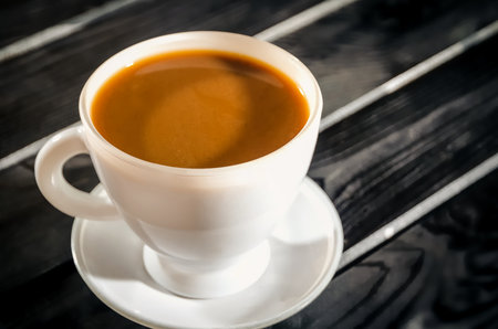 Hot coffee in a cup. Coffee in the cup on a black wooden table. Photo with a shallow depth of field.の写真素材