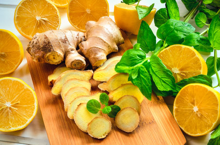 Lemons, ginger and mint leaves. Lemon halves, slices of ginger and mint leaves on a wooden board.