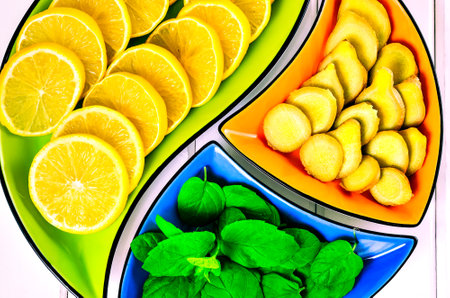 Concept with fresh fruits, vegetables and green spices. Lemon, ginger and mint leaves in colorful bowls.の写真素材