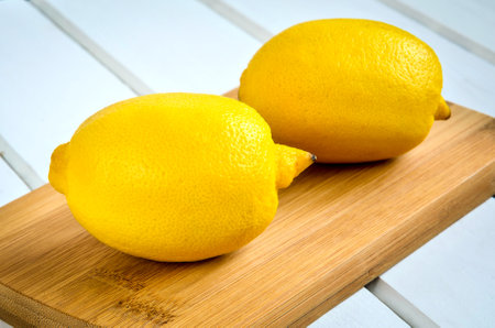 Yellow fruits on a white table. Lemons on chopping board on white wooden table.の写真素材