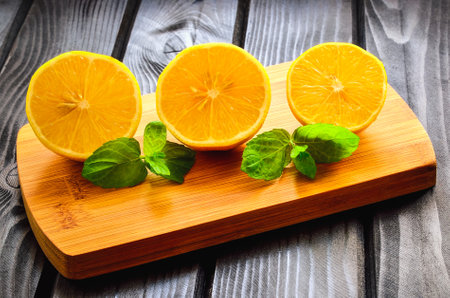 Lemons on a black wooden table. Lemon halves on a chopping board.の写真素材