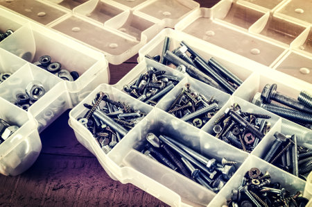 Silver and gold metal screws. Bolts and screws in plastic container.の写真素材