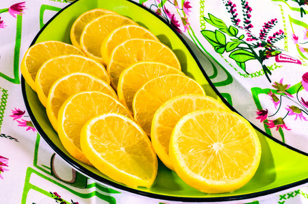 Concept with fresh yellow fruits. Slices of lemon in a bowl on a colorful cloth.の写真素材