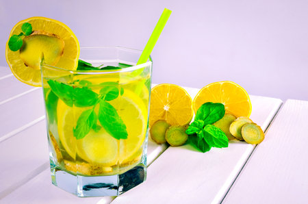 Drink in a glass on a white wooden table. Drink with lemon, ginger and mint.の写真素材