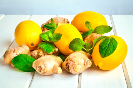 Concept with fresh fruits, vegetables and green spices. Lemons, ginger and mint leaves on a white wooden table.の写真素材