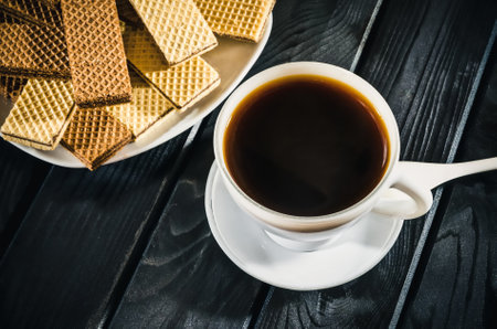 Table setting with cookies and coffee drink. Coffee with waffles on a black wooden table.の写真素材