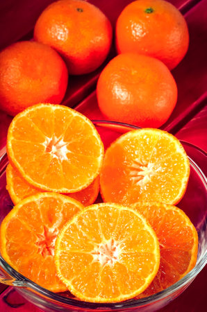 Orange citrus fruits. Half mandarins on a red wooden table.の写真素材