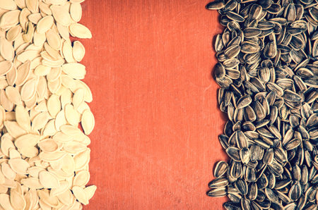 Pumpkin seeds and sunflower. Healthy food on the pile on a wooden table, may be used as background.の写真素材