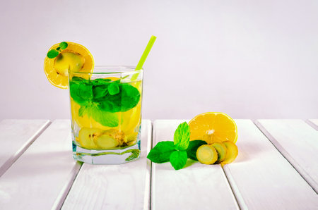 Drink in a glass on a white wooden table. Drink with lemon, ginger and mint.の写真素材