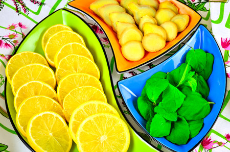 Concept with fresh fruits, vegetables and green spices. Lemon, ginger and mint leaves in colorful bowls.の写真素材