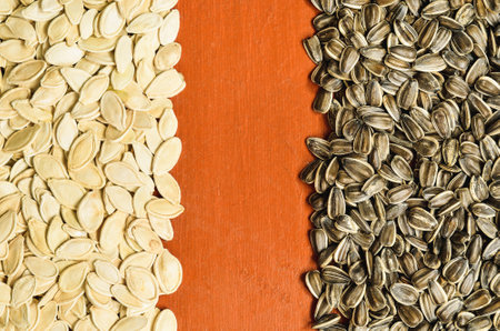 Pumpkin seeds and sunflower. Healthy food on the pile on a wooden table, may be used as background.の写真素材