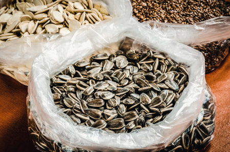 Sunflower with pumpkin seeds and linseeds in the background. Healthy food in foil bags.の写真素材