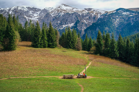 Western Tatra Mountains, Poland - May 10, 2016: Tourists resting on wooden benches with beautiful mountain peaks in the background.のeditorial素材