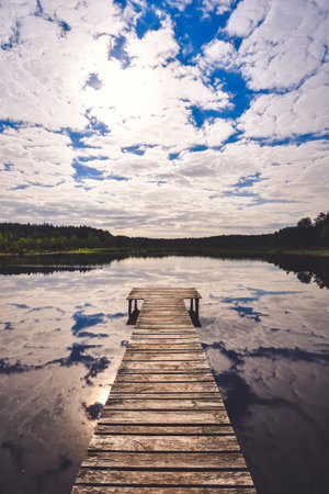 Beautiful summer afternoon landscape by the lake. Charming wooden pier over a small lake in Michala Gora, Poland.の写真素材