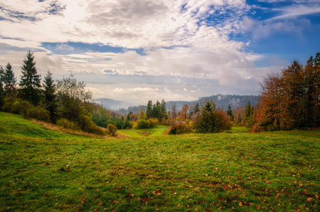 Countryside landscape. Glade in mountains in autumn with hills and forest at the background, Beskidy mountains, Poland.の写真素材