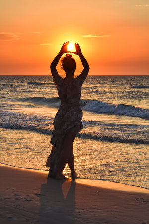 Woman on the seashore in a beautiful evening scenery. Girl walking on the beach with the setting sun in the background. Photo taken at the Baltic Sea in Leba, Poland.の写真素材
