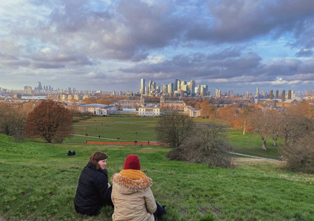 Two people sitting on a grassy area in London, overlooking the city.