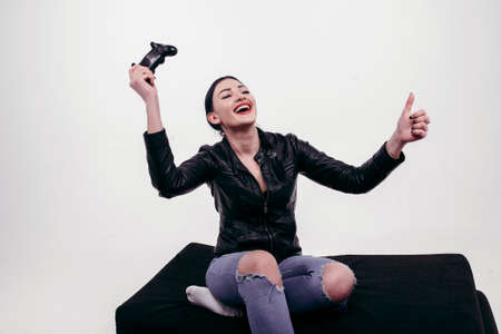 Beautiful girl playing with joystick in black jacket