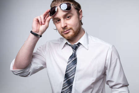 Portrait of young redhead man with beard white shirt and grey tie sunglasses isolatedの写真素材