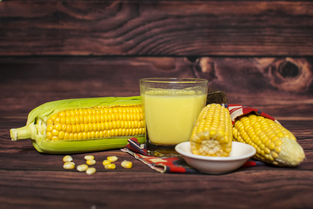 Fresh corn and milk on cobs on wooden table, closeupの写真素材