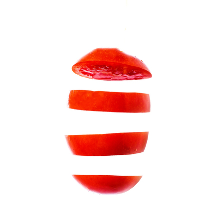 Flying slices of fruit: tomato on isolated white backgroundの写真素材