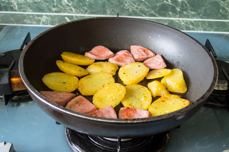 Fried boiled potato with fried sausage on a frying panの写真素材