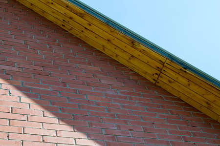 The brick wall and a roof against the sky