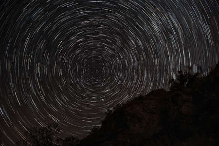 Star trails at night upon rocks with full circle around Polaris