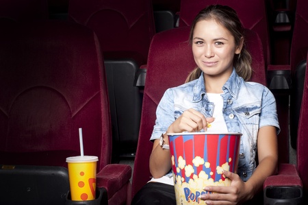 young woman sitting alone in the cinema and watching a movieの写真素材