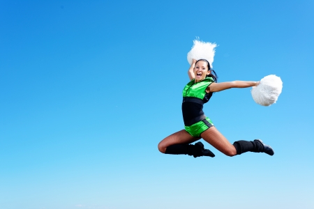 cheerleader girl jumping on a background of blue sky