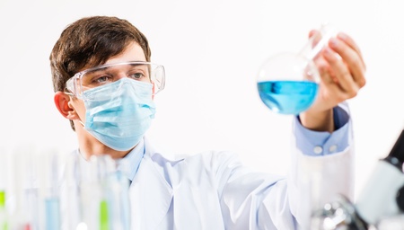 scientist working in the lab, in protective mask, examines a test tube with liquidの写真素材