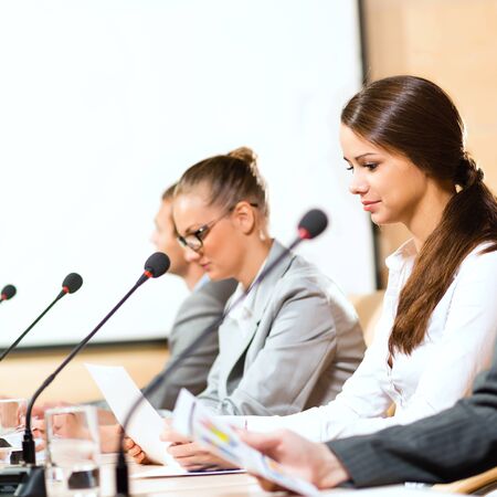 businessmen communicate at the conference, sitting at the table, on the table microphones and documentsの写真素材