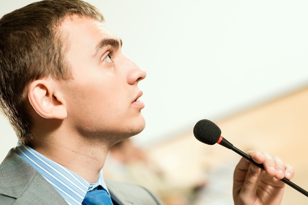 male speaker looks into the room and said into the microphone, speech at the conferenceの写真素材