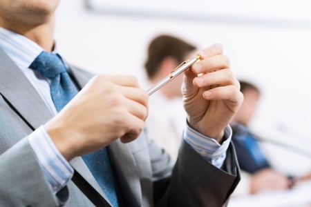 businessman sitting at a table and holding a penの写真素材