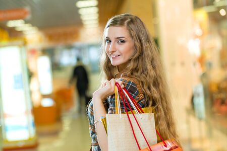portrait of a beautiful woman in a shopping center, holding shopping bags and smiling