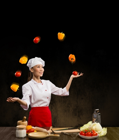 Asian woman chef juggling with vegetables, cooking skillsの写真素材