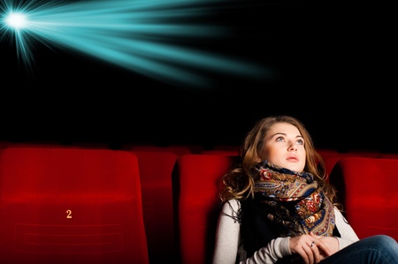 young attractive woman sitting in a cinema, enjoying a movieの写真素材