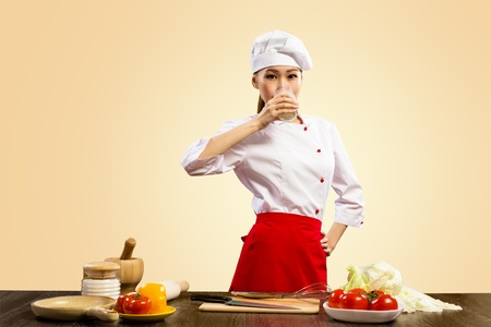Asian female cook drinking milk and looks aheadの写真素材