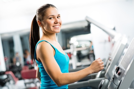 attractive young woman runs on a treadmill, is engaged in fitness sport club