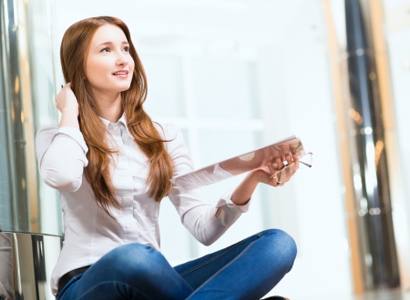 Portrait of an attractive woman sitting on the floor cross-legged and holds the tablet for notesの写真素材