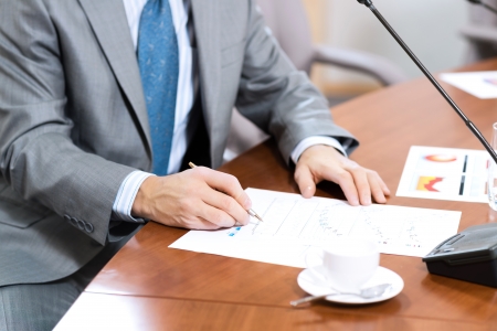 businessman taking notes, meeting businessmen at the table there are microphones and decomposition of business documentsの写真素材