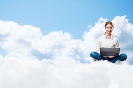 young girl running in the clouds with a laptop, place for textの写真素材