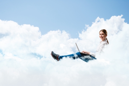 young girl running in the clouds with a laptop, place for textの写真素材