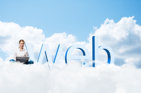 girl sitting cross-legged on the clouds with the laptop, next to the letters WEBの写真素材